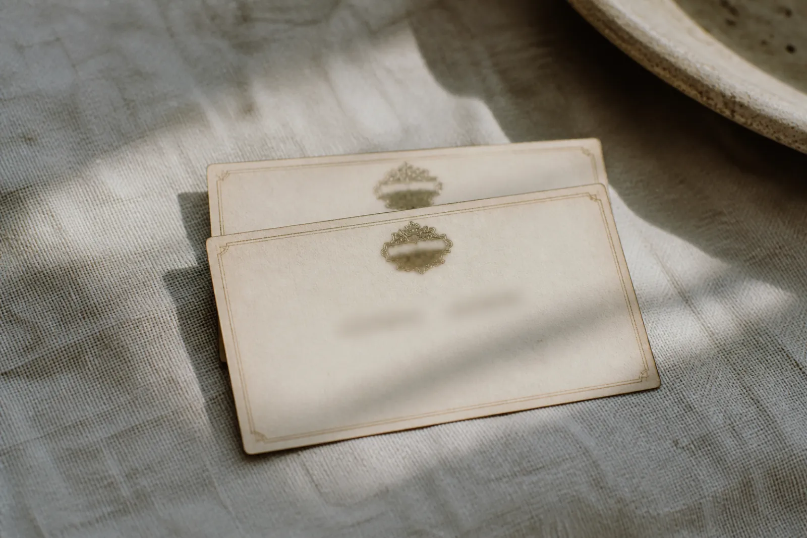 Two nearly identical cream name cards overlapping on linen, slightly misaligned. Editorial photograph for this article; no person is identified.